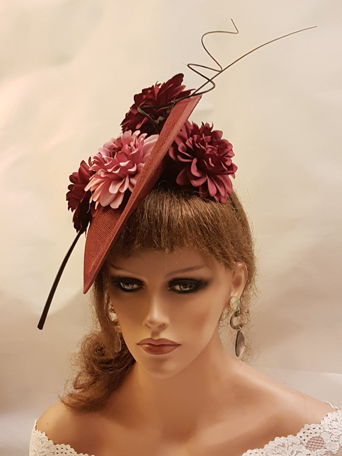 burgundy hat with a wide brim and a black wire accent. The hat is decorated with pink and burgundy fabric flowers.