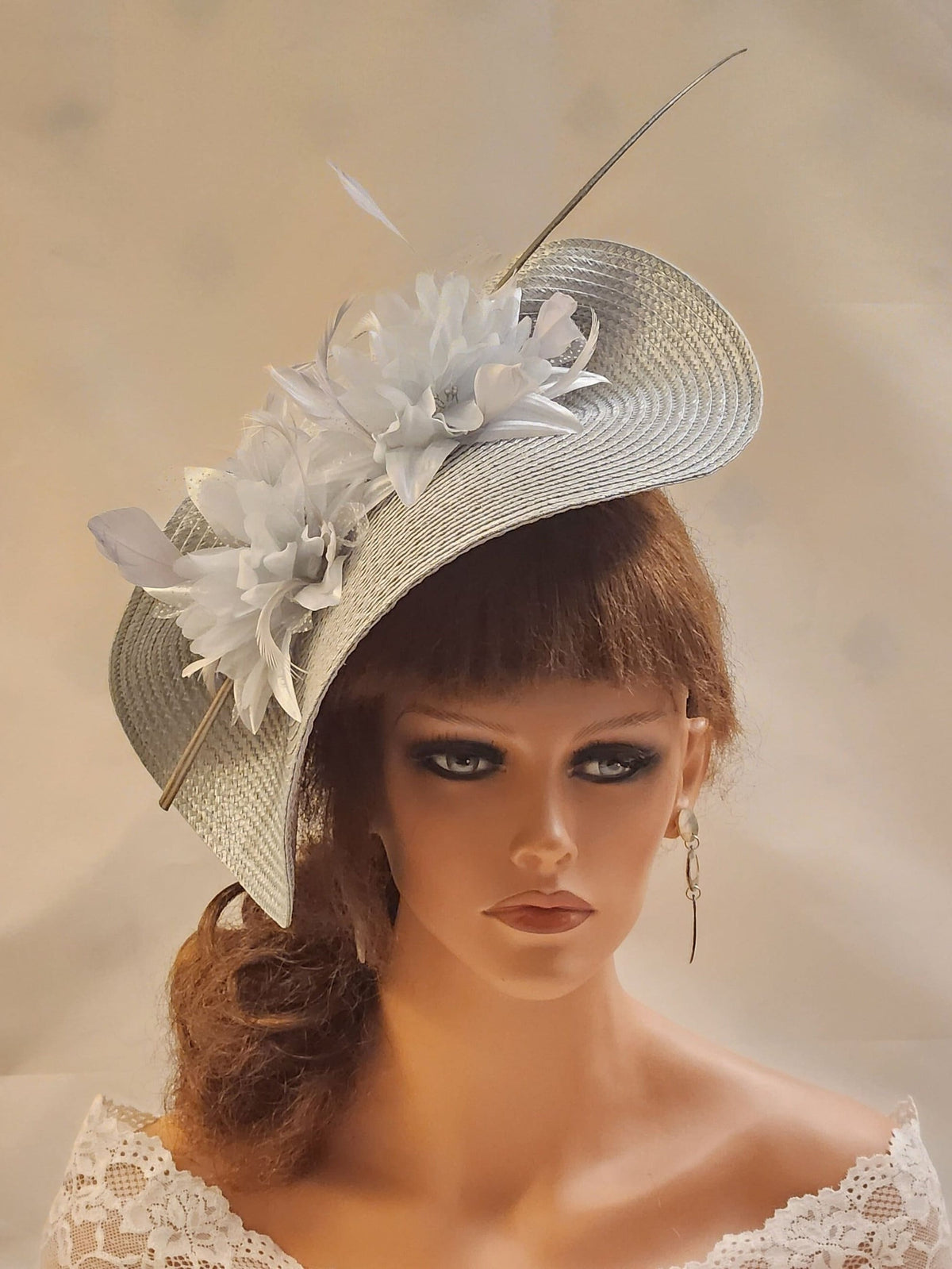 A silver straw hat with a large, silver flower,Pearls  and feather.