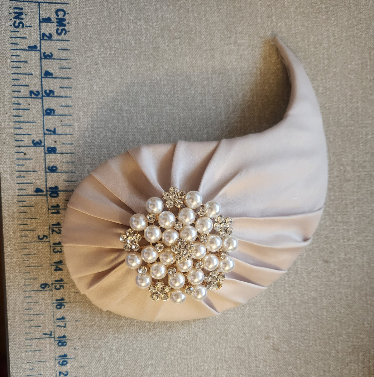 Bridal hat hair accessory with a large pearl and rhinestone embellishment.