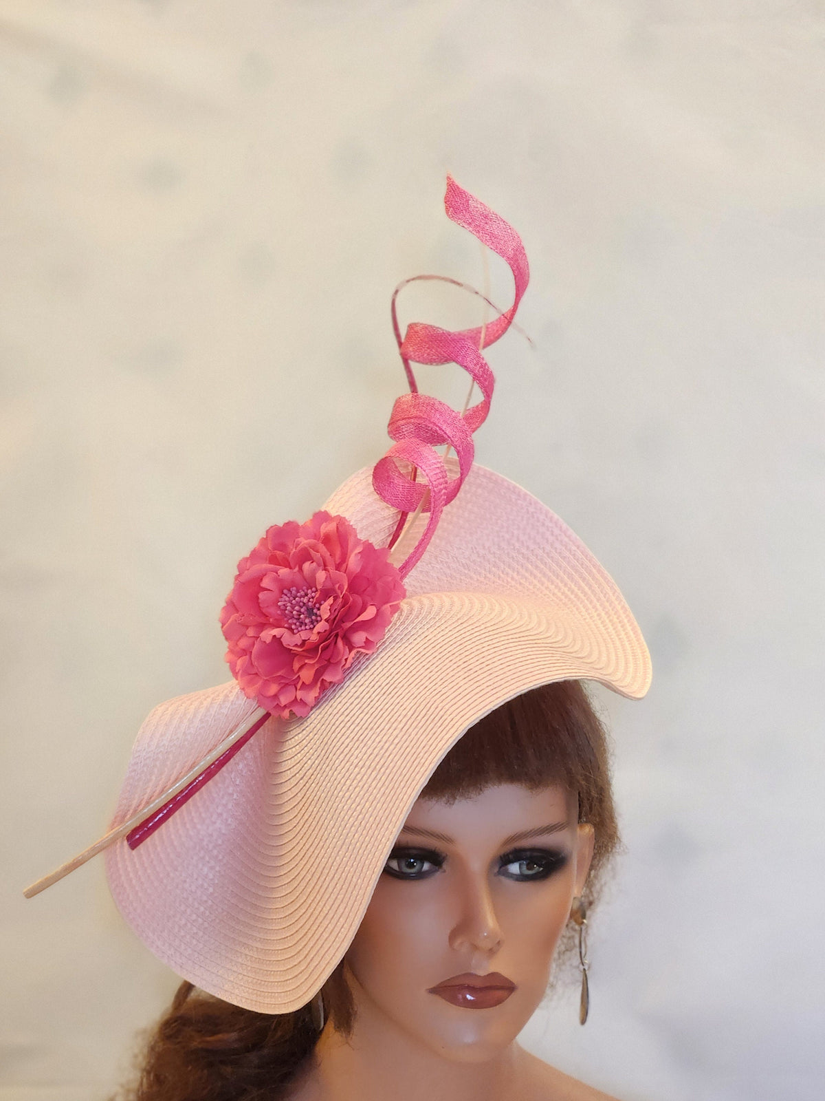 pink wide-brimmed hat with a pink flower and a pink ribbon accent.