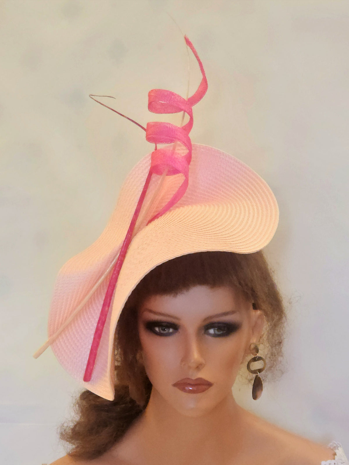 pink straw hat with a pink ribbon accent. The hat is tilted at an angle and has a wide brim.