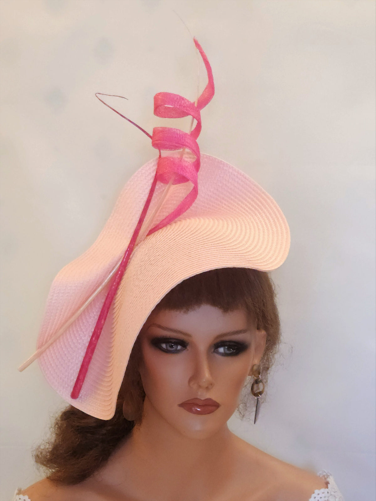 pink hat with a large, wavy brim and a pink ribbon curled on top.