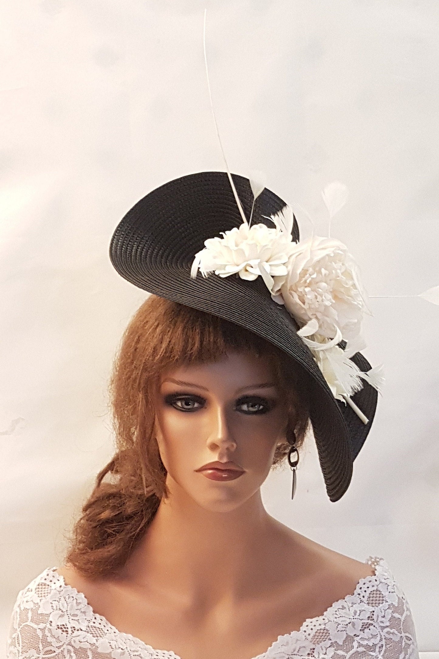 A black and white hat with a large white flower and feathers.