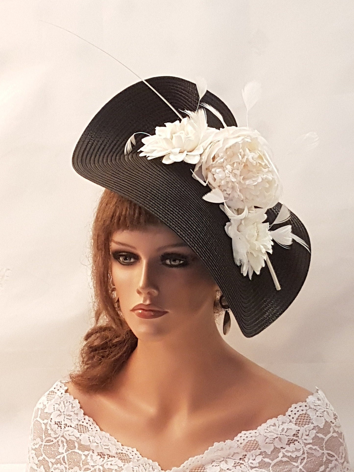 black wide-brimmed hat with a white flower and feather embellishment.