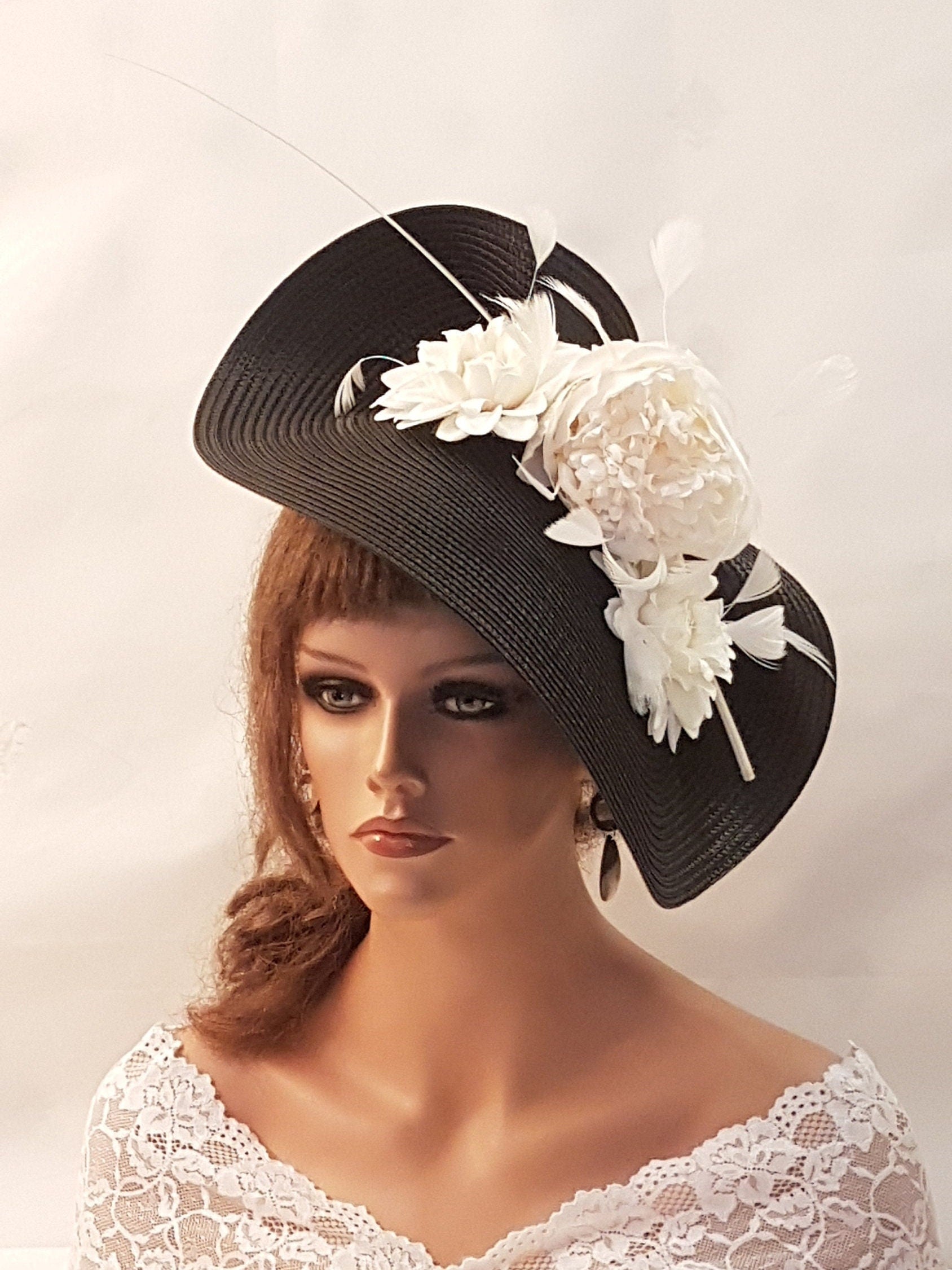 black wide-brimmed hat with a white flower and feather embellishment.
