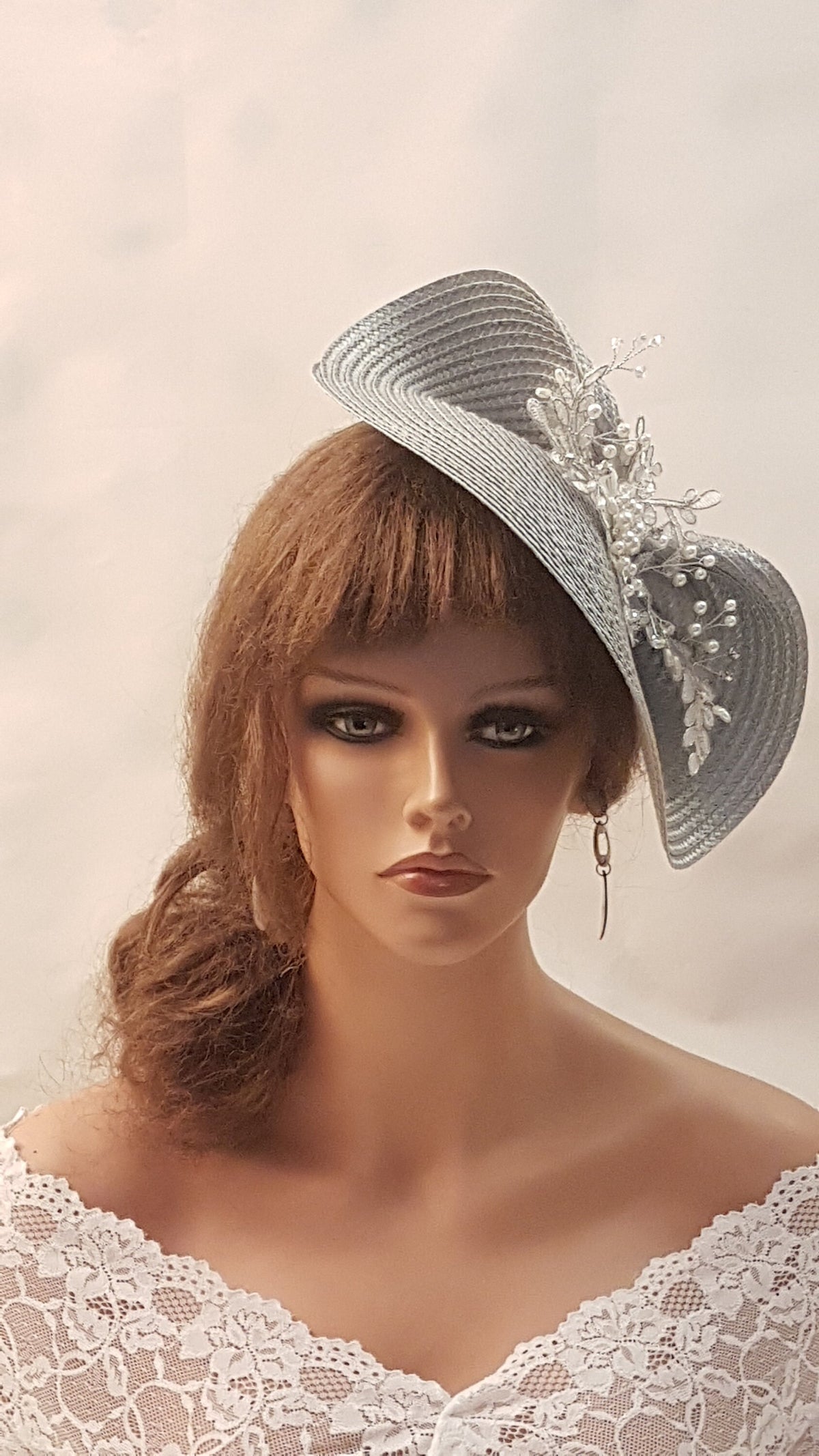 A silver hat with a white beaded vine.