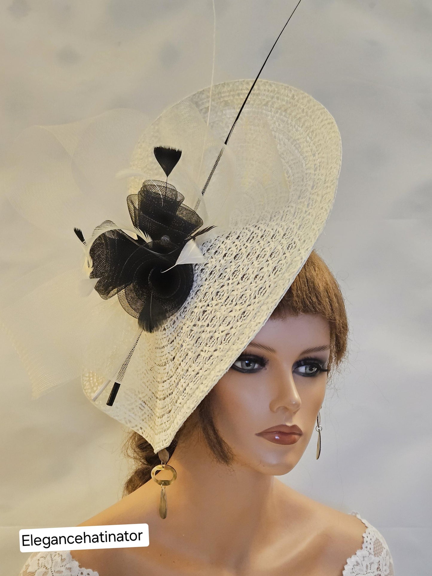 Ivory fascinator hat with a black feather and a black flower accent.