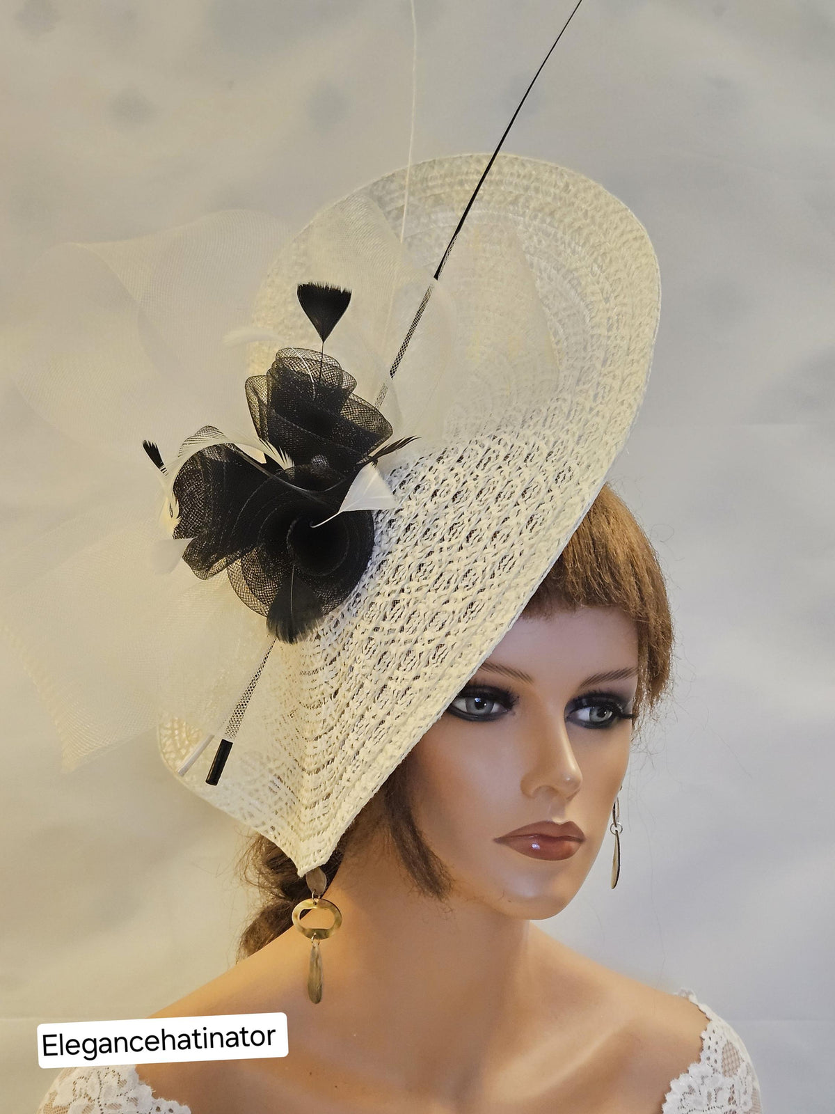 Ivory fascinator hat with a black feather and a black flower accent.