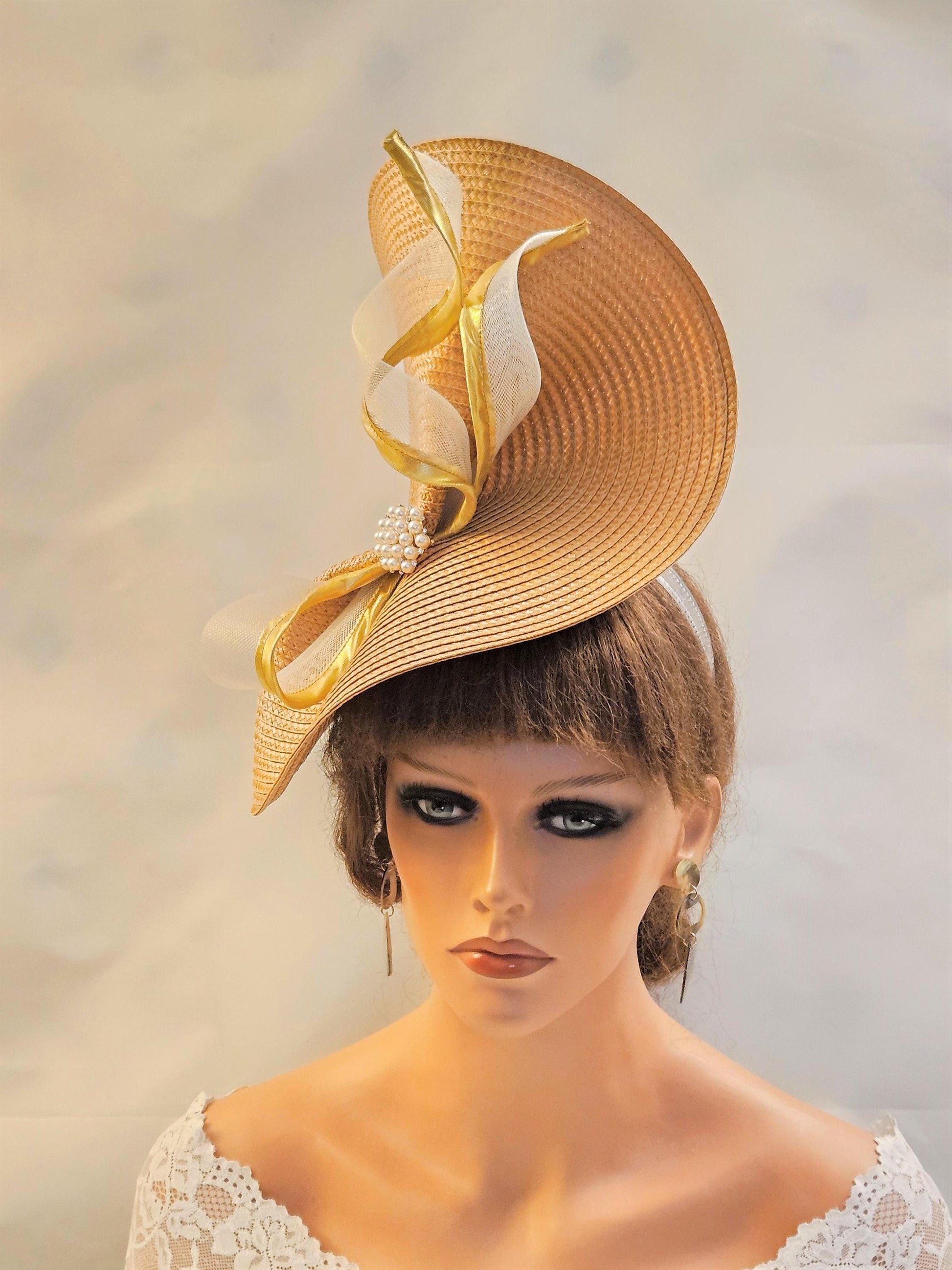 stylish Mustard Gold straw fascinator hat features a dramatic, asymmetrical design. Gold edge Crinoline Swril accents add a touch of elegance with a pearl and Crystal jewel. Perfect for wedding,Royal Ascot, Race, Kentucky Derby & special occasions.