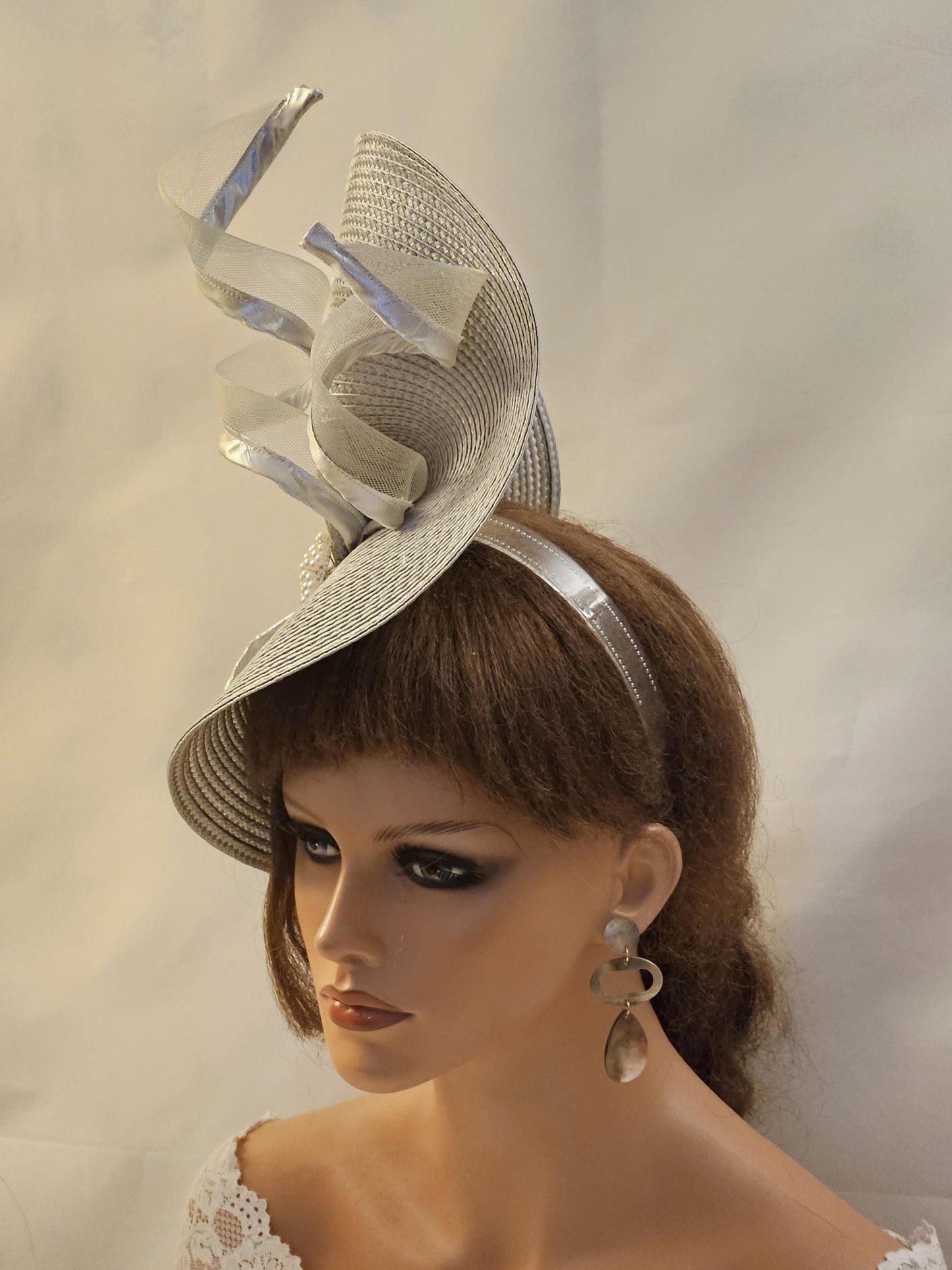 Silver PP straw weave fascinator hat with 
crinoline  ribbon accents.  Features a wide brim and a sculpted crown. It's adorned with elegant, cascading silver ribbons. A dramatic &  stylish design.Headpiece is perfect weddings & Races