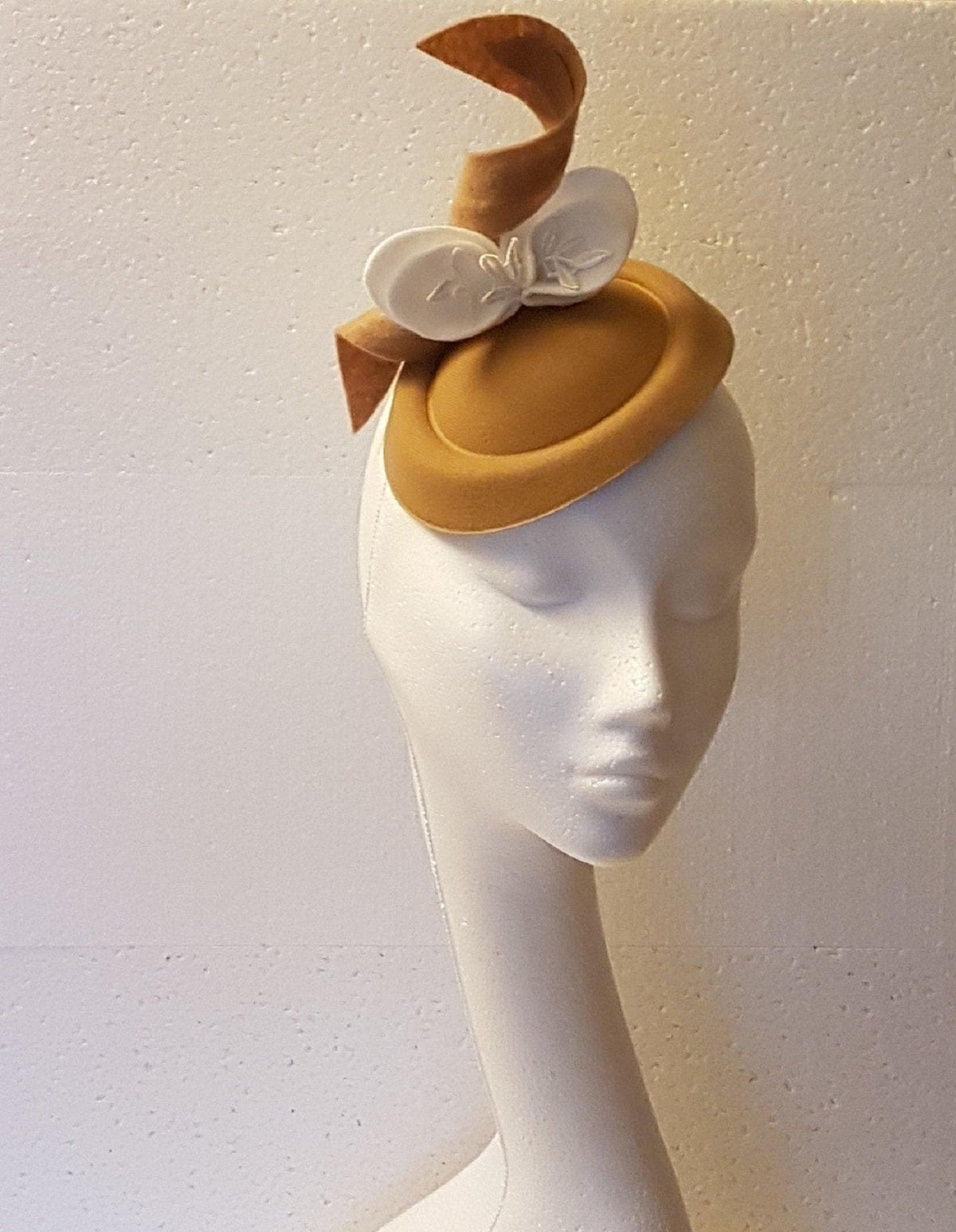 tan felt hat with a white felt bow and a tan felt ribbon.