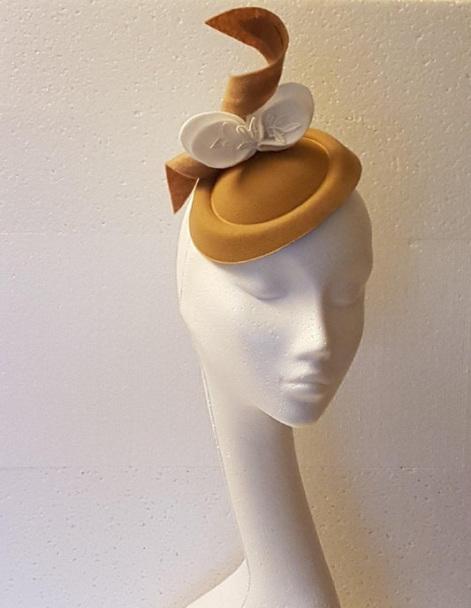 tan felt hat with a white felt bow and a tan felt ribbon.