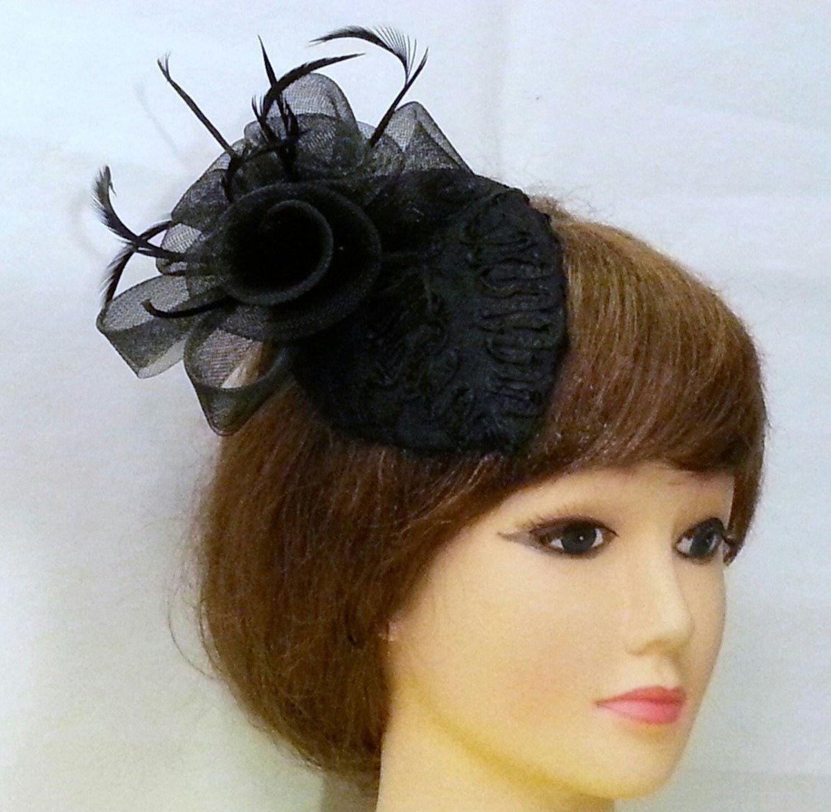 black hair accessory with a small, teardrop hat base and a black mini  veil with feathers.