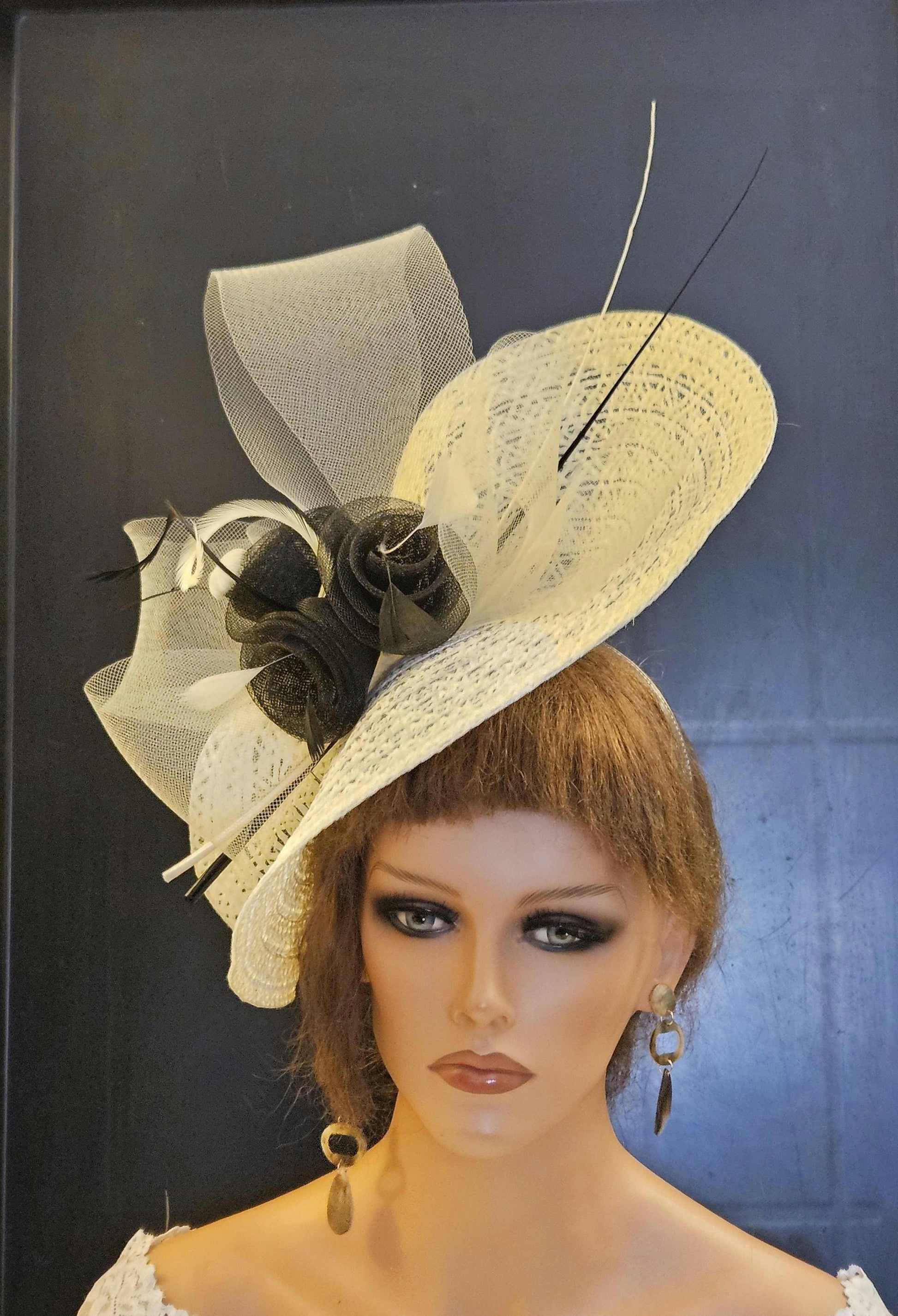 Ivory and black hat with a large brim and a black flower accent. The hat is made of a delicate, woven material and has a soft, feminine feel.