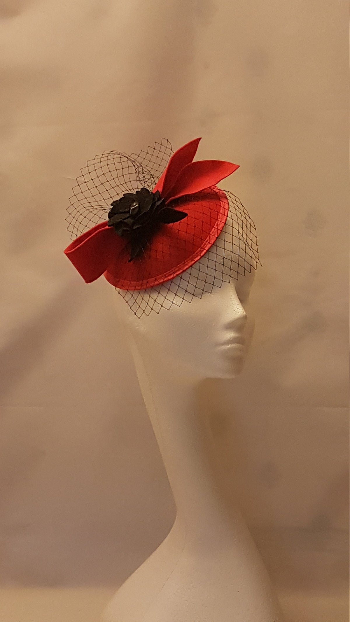 red felt hat with a black flower and a black net veil.