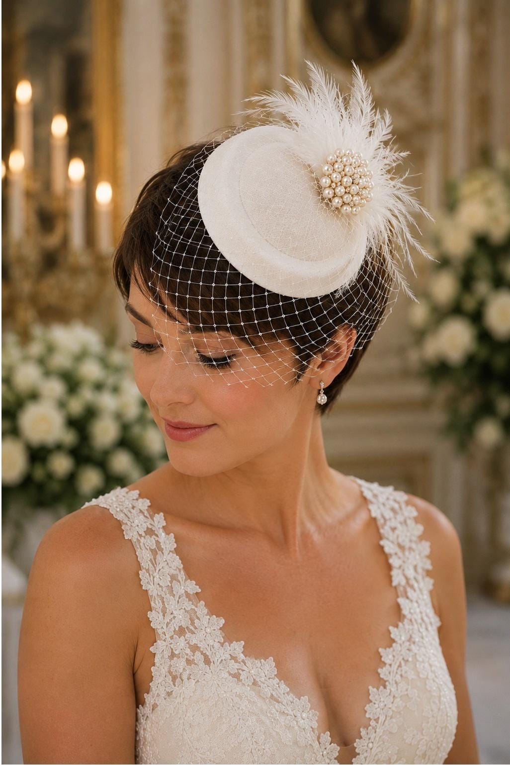 May include: A cream-coloured fascinator hat featuring a round base, a delicate white birdcage veil, and a decorative cluster of white feathers accented with a central arrangement of small, round, lustrous white pearls.