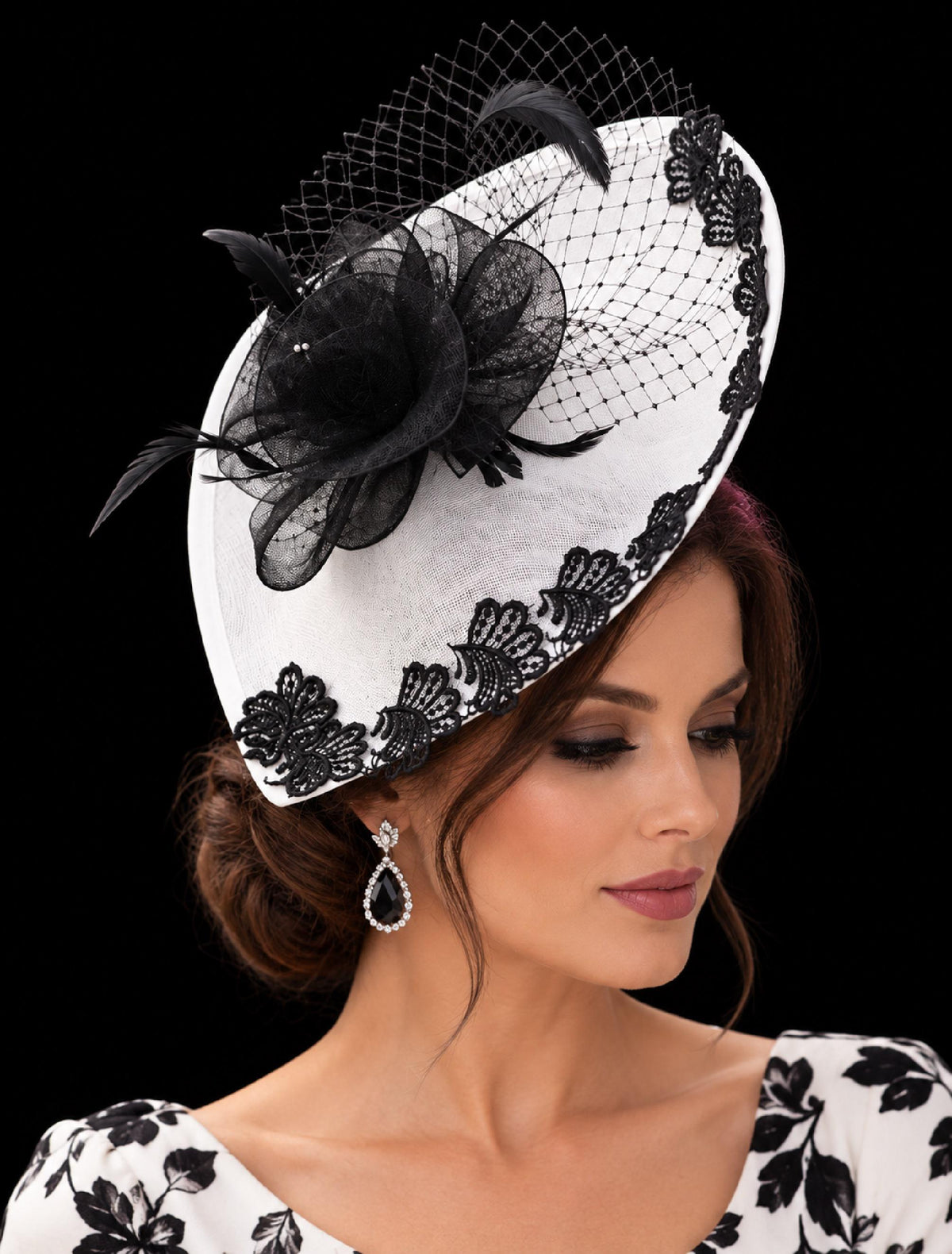 White fascinator hat with black lace trim, black flower, feathers and birdcage netting.